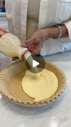 a person pouring batter into a pie crust