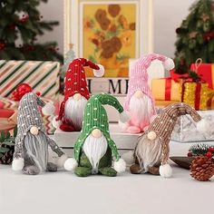 christmas gnomes sitting in front of presents on a table with pine cones and candy canes