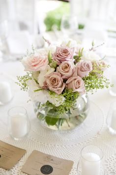 a vase filled with pink and white flowers on top of a table next to candles