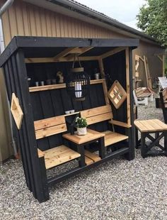 a wooden bench sitting in front of a shed with shelves and benches on the outside