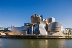 a large building sitting on top of a river next to a tall body of water