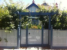 a white fence with a blue gate in front of it