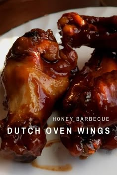 two pieces of meat on a white plate with the words, honey barbecue dutch oven wings