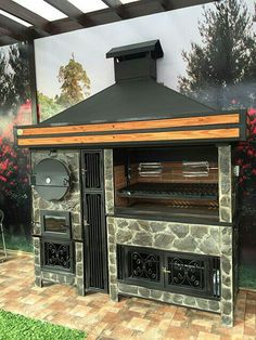 an outdoor bbq grill is shown in front of a wall with trees and flowers on it