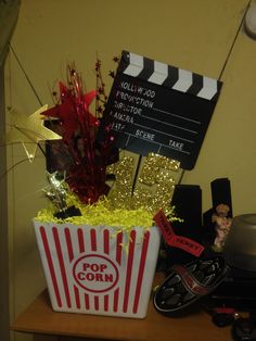 a popcorn bucket filled with candy next to a movie clapper