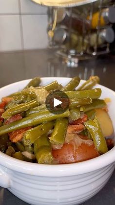 a white bowl filled with green beans and carrots on top of a kitchen counter