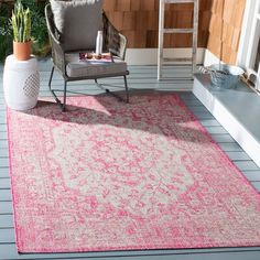 an outdoor area with a chair, potted plant and pink rug on the floor