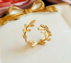 A lovely open Laurel wreath ring features small leaves wrap around your finger. Ring is adjustable to fit any size.  Ring is brass with gold plating. Enjoy! Purchase over $40 enjoys free shipping! Coupon code 'freeshipping1'. Free Gift Wrapping on request - All items that are gift wrapped come in with a kraft box with raffia string and blank writing card.  Please leave a note if you need it upon ordering. Laurel Ring, Laurel Wreath Ring, Gold Leaf Ring, Wreath Ring, College Rings, Botanical Ring, Ring Wreath, Wreath Rings, Ribbon Ring