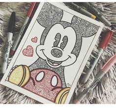 some markers and pens are laying next to a coloring book with an image of mickey mouse