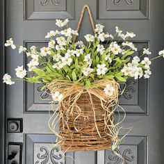 a basket filled with white flowers hanging from a door