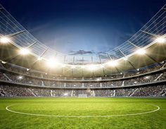 an empty soccer stadium with the lights on and fans in the stands looking at the pitch