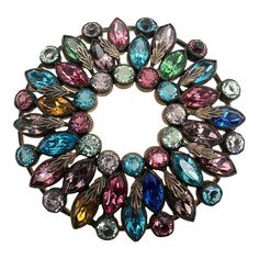 This is part of Chairish’s Costume Jewelry assortment.  A wonderful colorful wreath form brooch dating from the 1950s.  The piece has prong set marquis and round faux gemstones with applied leaf decoration.  It is quite sizable and makes a statement.  Dimensions: Diameter: 2 1/8", Weight: 28.2 grams Vintage Multicolor Round Brooches, Vintage Multicolor Multi-stone Brooch, Gemstone Brooch, Leaf Decoration, Colorful Wreath, Wreath Form, Wreath Forms, Leaf Decor, The 1950s