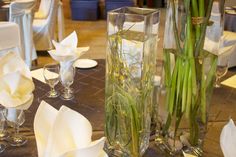 two tall vases filled with water and flowers on top of a dining room table