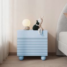 a blue toy chest sitting on top of a wooden floor next to a white bed