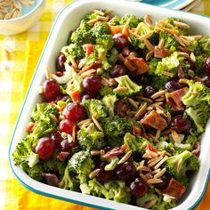 a salad with broccoli, grapes and nuts in a white bowl on a yellow tablecloth