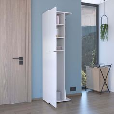 a tall white bookcase next to a door in a room with blue walls and wooden floors