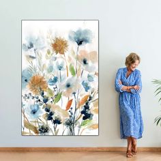 an older woman standing in front of a painting on the wall with her arms crossed