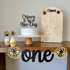 a table topped with cupcakes and cake next to a sign that says one