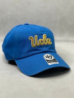 This is a baby blue UCLA adjustable clean up hat that is hand embellished with genuine transparent yellow Swarovski crystals on the front logo.  This hat features over 150+ varying size Swarovski style crystals.  - 100% Cotton - Matching fabric strap & buckle  - One Size Fits All - Raised Embroidered Logo - 150 + Swarovski style transparent yellow crystals individually placed by hand - Ready to ship in 1 week from San Diego, CA Adjustable Gold Hat With Rhinestones, Gold Adjustable Hats With Rhinestones, Blue Adjustable Hat With Rhinestones, Adjustable Blue Hat With Rhinestones, Rhinestone Football, Bling Hat, Yellow Crystals, Sports Hat, Sport Hat