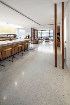 an empty room with bar stools and tables in the center, near large windows