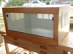 a wooden table topped with a glass case on top of it's shelf next to a window