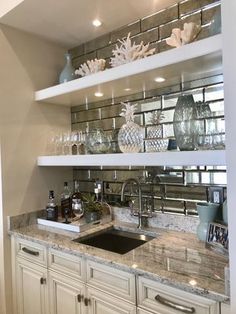 a kitchen with white cabinets and shelves filled with glassware on top of the counter