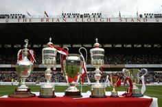 the trophies are lined up on a table in front of an empty stadium bleachers