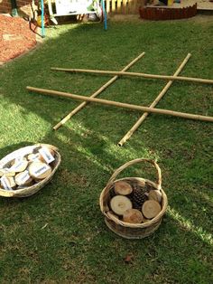 two baskets filled with logs sitting on top of a grass covered field next to a ladder