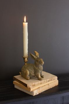 a candle that is sitting on top of a book with a rabbit figurine next to it