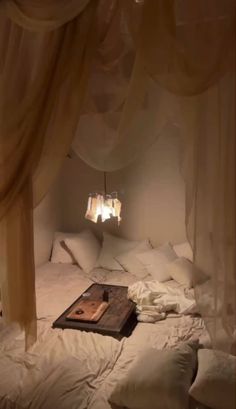 an unmade bed with white sheets and drapes hanging from it's ceiling