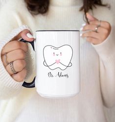 a woman holding a coffee mug with a cartoon tooth on the front and words dr thomas