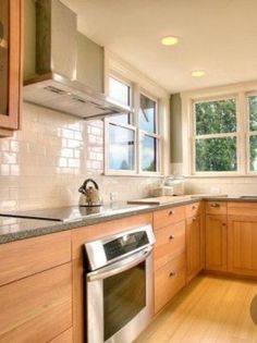 an empty kitchen with wooden cabinets and stainless steel appliances in the center, along with hardwood flooring