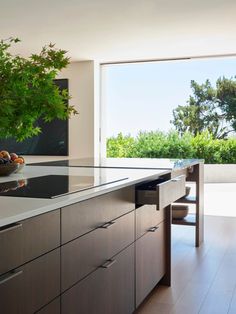 a modern kitchen with an island countertop and large windows looking out onto the outdoors