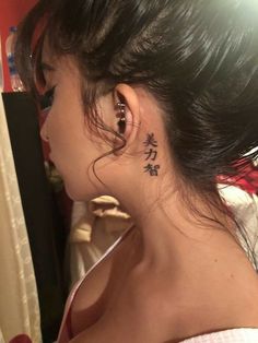 a woman wearing ear piercings with chinese writing on her left side behind her ear