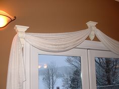 an open window with white drapes and a light hanging from the ceiling next to it