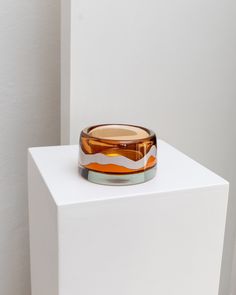 a small glass bowl sitting on top of a white block