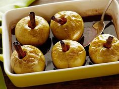 four apples are in a yellow dish with spoons