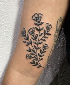 a black and white photo of a flower tattoo on the left upper arm or leg