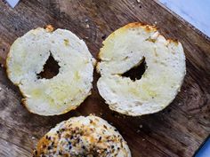 three bagels sitting on top of a wooden cutting board next to eachother