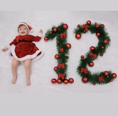 a baby is laying in the snow next to christmas decorations and letters that spell out 2013