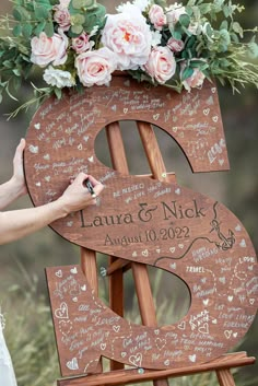 a wooden easel with flowers and writing on it