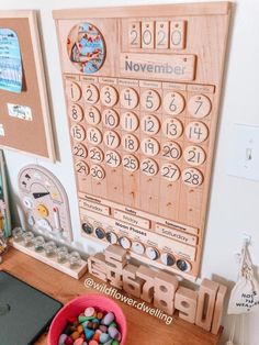 a wooden calendar on a wall next to a pink bowl filled with candy and candies