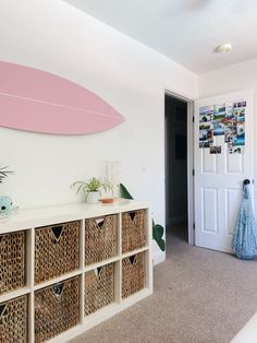 a living room with a surfboard on the wall and wicker baskets in front of it