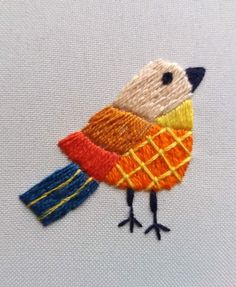 an embroidered bird with orange, yellow and blue colors