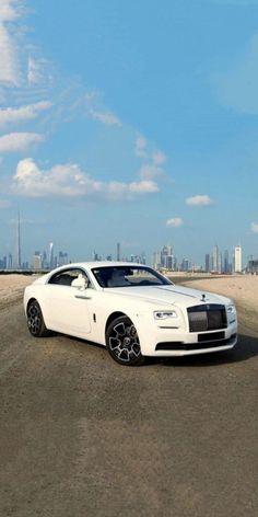 a white rolls royce parked on the beach