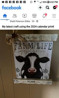 a wooden sign with a cow painted on it's face hanging from the ceiling