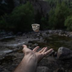 a hand reaching for a rock in the middle of a river