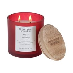 a red candle sitting next to a wooden container on a white background with the words better homes and gardens printed on it