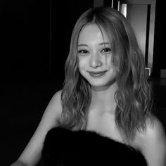 black and white photograph of a woman in a fur vest smiling at the camera with her hands on her hips