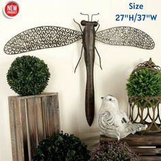 a dragonfly statue sitting on top of a wooden table next to potted plants